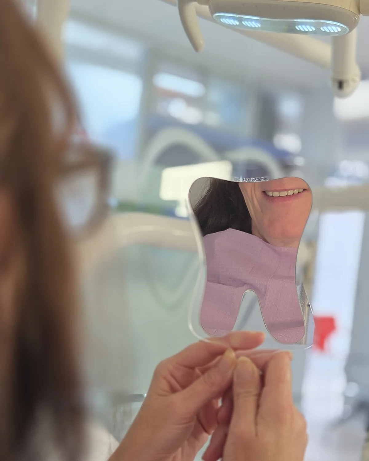 Paciente sonriendo en espejo durante consulta en Salud Urbana, clínica odontológica en Villa Ballester